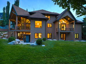 Back of house featuring a balcony, a lawn, a patio area, stucco siding, and a shingled roof
