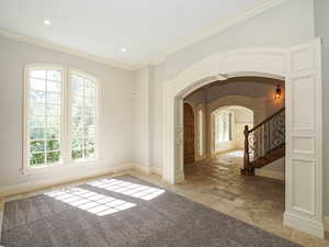 Living Room with arched walkways, stone tile floors, ornamental molding, and recessed lighting