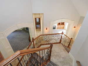 Staircase with a high ceiling, arched walkways, stone finish floors, and carpet floors