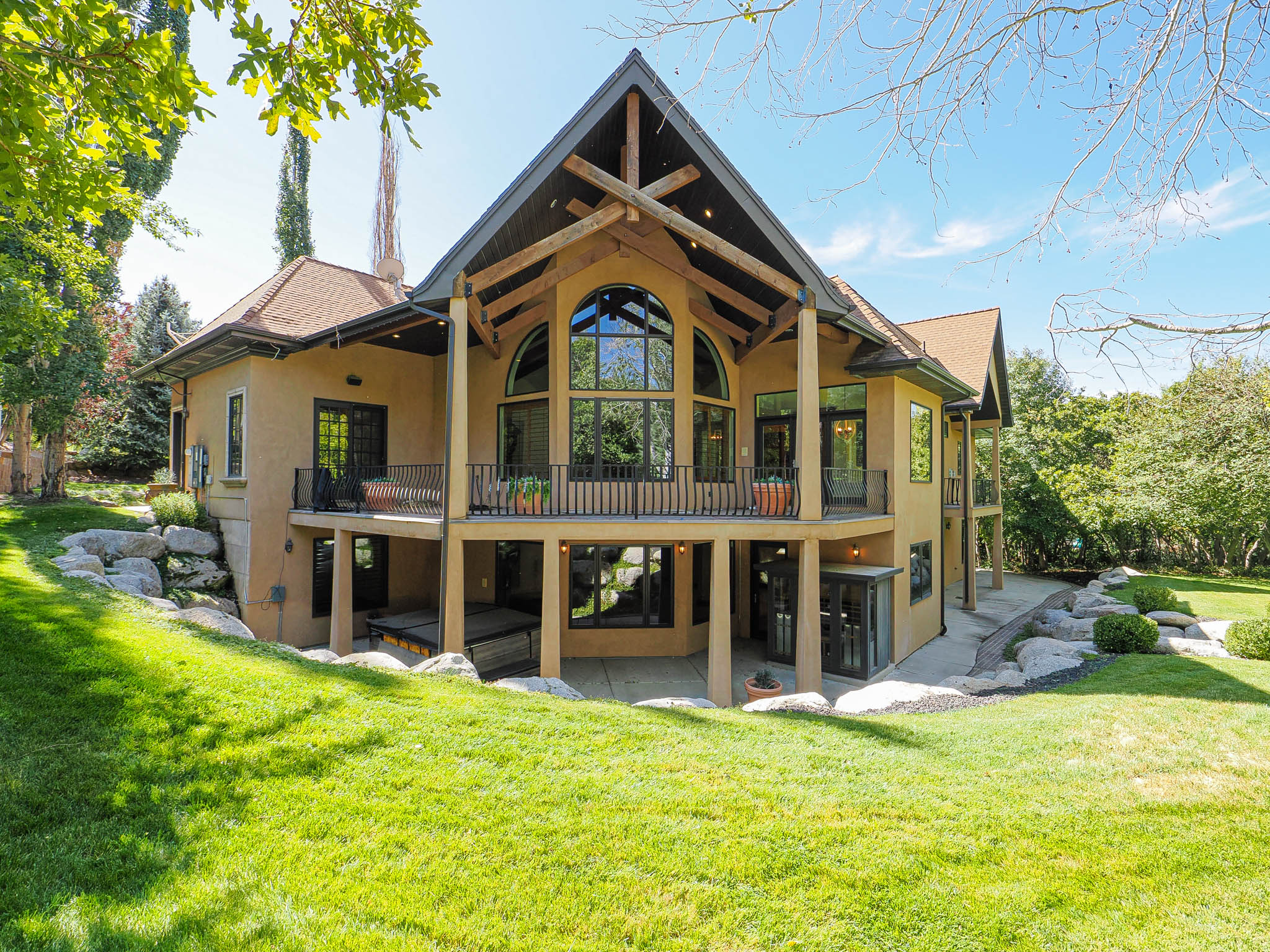 Back of house with stucco siding, a patio area, a balcony, and a yard