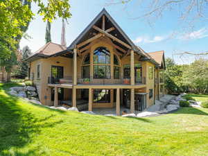 Back of house with stucco siding, a patio area, a balcony, and a yard