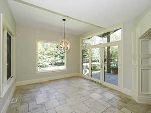 Unfurnished dining area with stone tile flooring and a chandelier