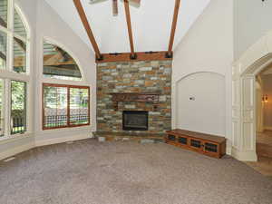 Unfurnished living room with vaulted ceiling, arched walkways, carpet flooring, a fireplace, and ceiling fan