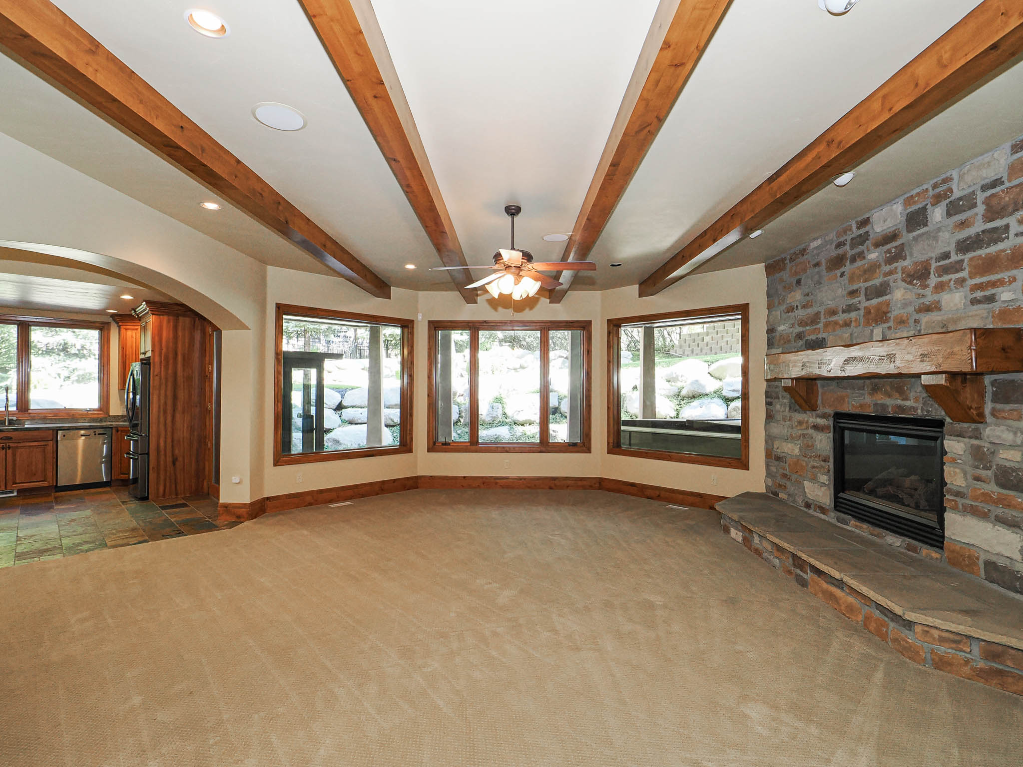 Unfurnished living room featuring a fireplace, healthy amount of natural light, carpet floors, recessed lighting, and beamed ceiling