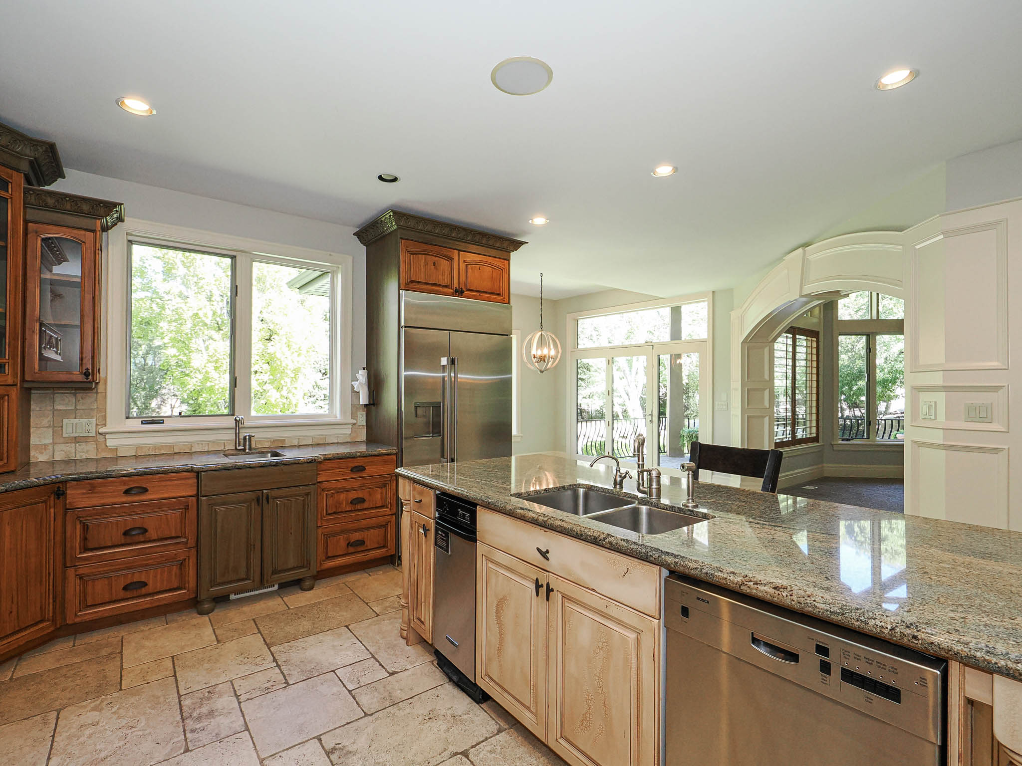 Kitchen featuring stainless steel appliances, dark stone countertops, glass insert cabinets, stone tile floors, and healthy amount of natural light