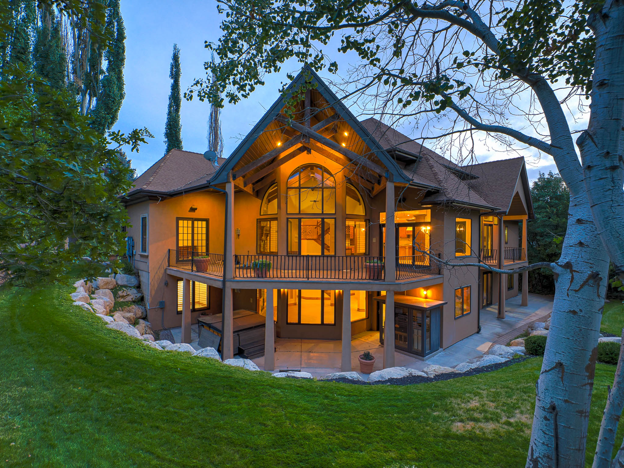 Rear view of property featuring a patio area, stucco siding, a lawn, and a balcony