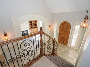 Foyer entrance with stone tile flooring, lofted ceiling, and a glass covered fireplace