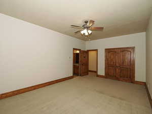 Unfurnished bedroom featuring light colored carpet, a ceiling fan, a closet, and connected bathroom