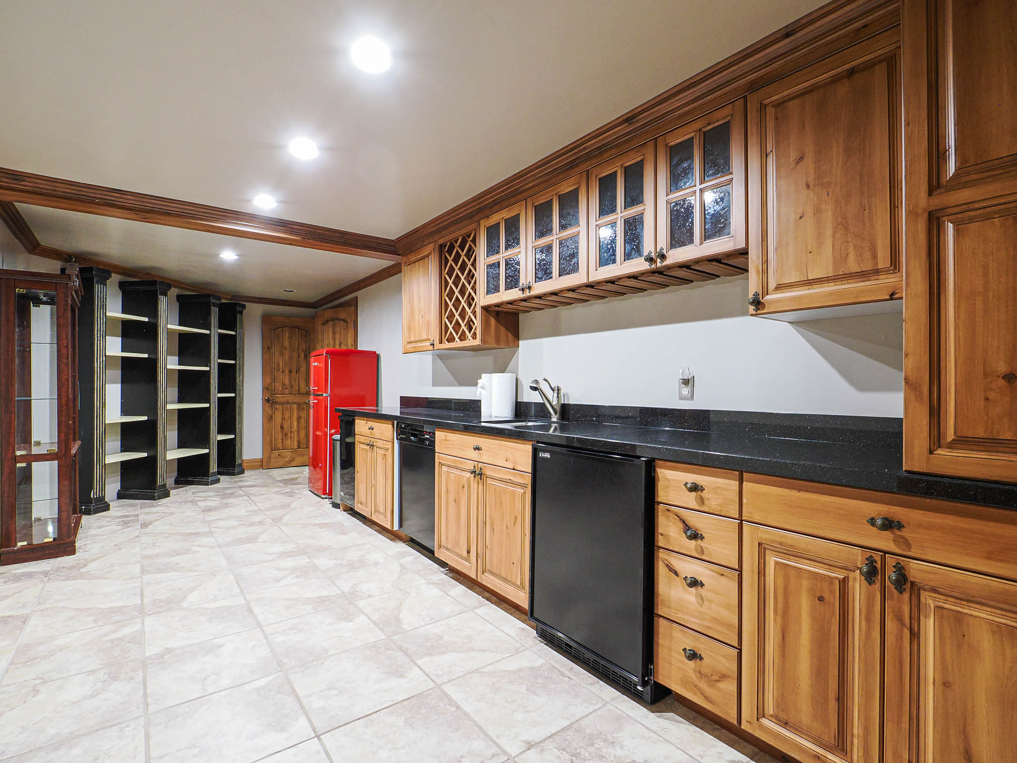 Kitchen with glass insert cabinets, ornamental molding, recessed lighting, freestanding refrigerator, and dark stone counters