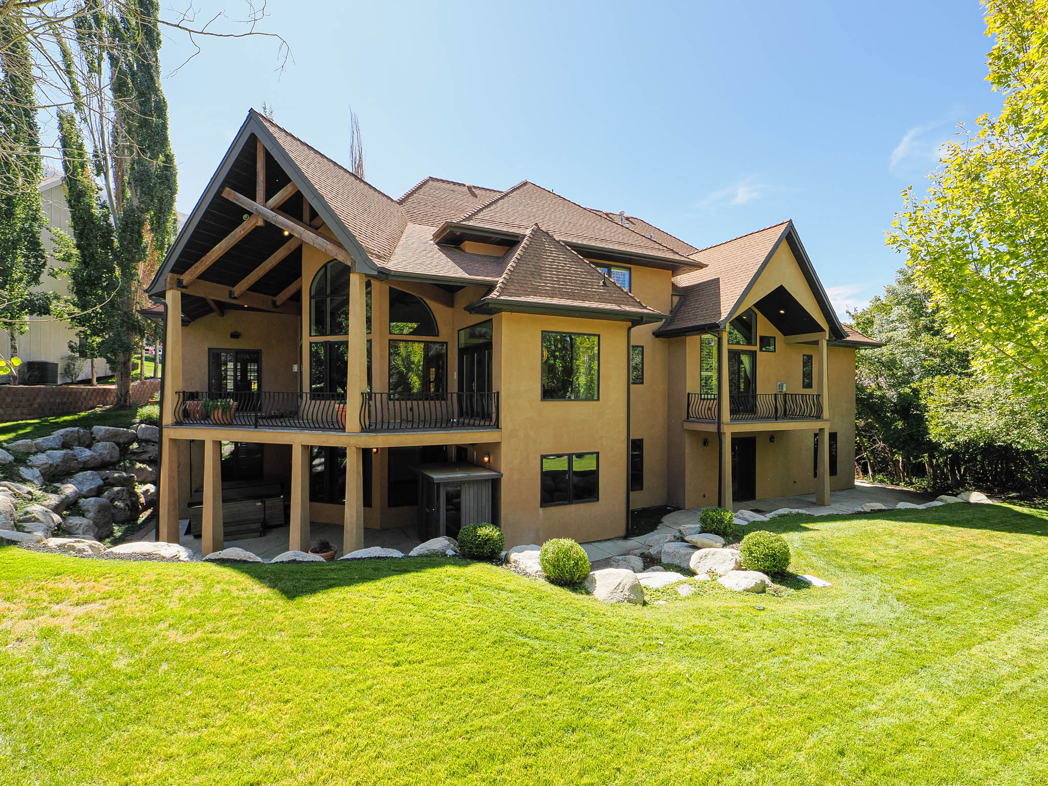 Rear view of house featuring a yard, a shingled roof, stucco siding, and a patio