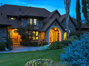 View of front of home with stone siding, a lawn, stucco siding, and french doors