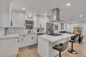 Kitchen featuring a center island, island range hood, light wood finished floors, white cabinets, and recessed lighting