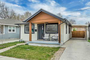 View of front of home with covered porch, an attached carport, a front yard, and concrete driveway
