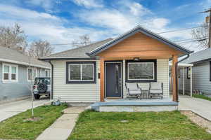 Bungalow with a front yard, a porch, and a shingled roof
