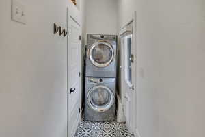 Laundry area featuring stacked washer / drying machine and light tile patterned floors
