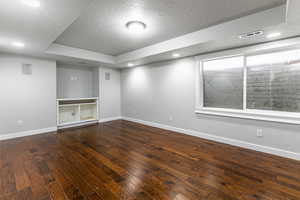 Below grade area featuring dark wood finished floors, recessed lighting, and a textured ceiling