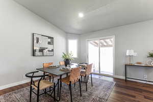 Dining room with vaulted ceiling and dark wood-style floors