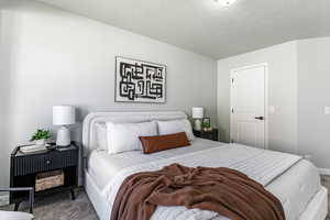 Carpeted bedroom with a textured ceiling and baseboards