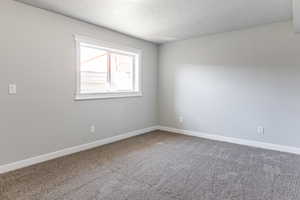 Carpeted empty room featuring baseboards and a textured ceiling