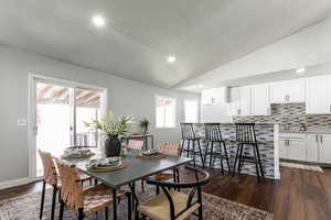 Dining area featuring dark wood finished floors, vaulted ceiling, and recessed lighting