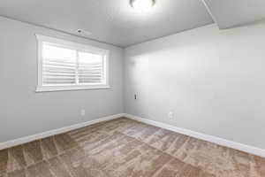 Spare room with a textured ceiling and light colored carpet