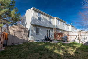 Rear view of house featuring a fenced backyard, a storage shed, and a patio