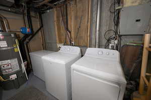 Laundry area with electric panel, secured water heater, concrete flooring, and washer and clothes dryer