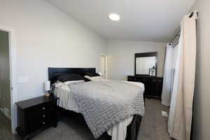 Bedroom with lofted ceiling and dark colored carpet
