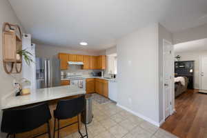 Kitchen featuring a peninsula, stainless steel appliances, a breakfast bar, light tile patterned floors, and recessed lighting