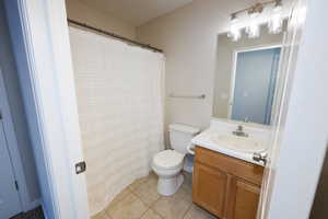 Full bath featuring vanity, curtained shower, and light tile patterned flooring