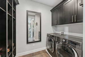 Laundry room with cabinet space, dark wood-style flooring, and washing machine and clothes dryer