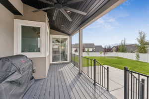 Wooden terrace with ceiling fan, area for grilling, and a residential view