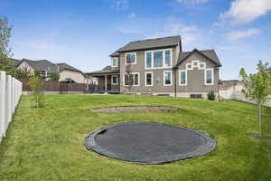Back of property with a trampoline, a fenced backyard, and stucco siding