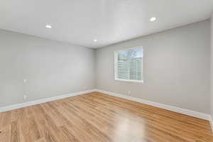 Empty room with light wood finished floors, recessed lighting, and a textured ceiling