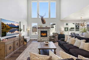Living area featuring a chandelier, wood finished floors, a fireplace, and a high ceiling