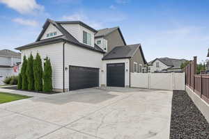 View of side of property featuring a gate, driveway, and roof with shingles