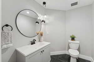 Half bathroom featuring vanity and dark marble finish floors