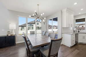 Dining room with suspended lighting, dark wood-style floors, and plenty of natural light