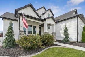 View of front of house featuring board and batten siding, roof with shingles, covered porch, and a front yard