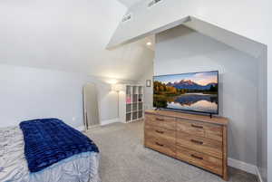 Bedroom featuring light carpet and lofted ceiling
