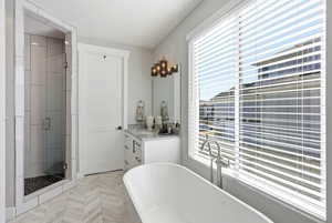 Bathroom featuring vanity, a stall shower, and a freestanding tub