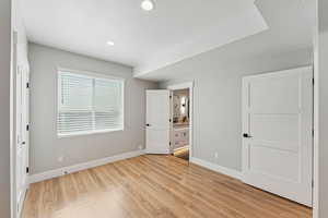 Unfurnished bedroom featuring light wood-style floors, ensuite bathroom, a textured ceiling, and recessed lighting