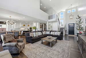 Living area with a chandelier, dark wood-type flooring, and a high ceiling