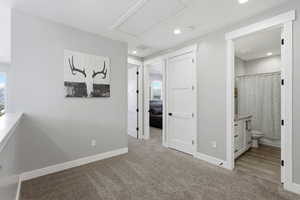 Hallway with light colored carpet and attic access