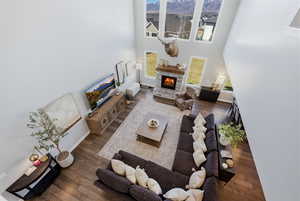 Living room with a high ceiling, dark wood-style flooring, and a stone fireplace