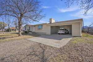 Single story home featuring concrete driveway, a chimney, and a garage