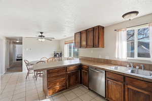Kitchen featuring a peninsula, dishwasher, light tile patterned floors, a textured ceiling, and ceiling fan
