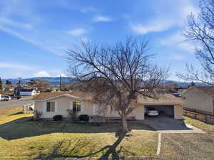 View of side of home featuring a mountain view, driveway, an attached garage, and roof with shingles