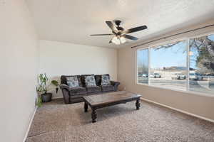 Living area featuring light carpet, a textured ceiling, and ceiling fan