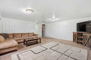 Carpeted living room featuring a textured ceiling and wood walls